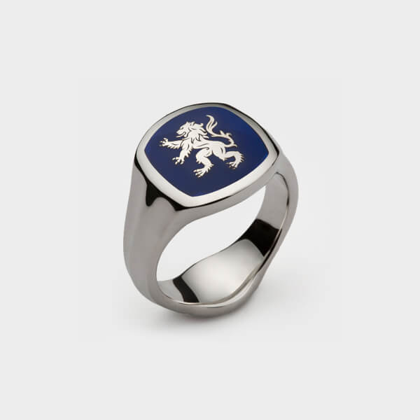 A platinum signet ring with a dragon design and blue enamel on it.